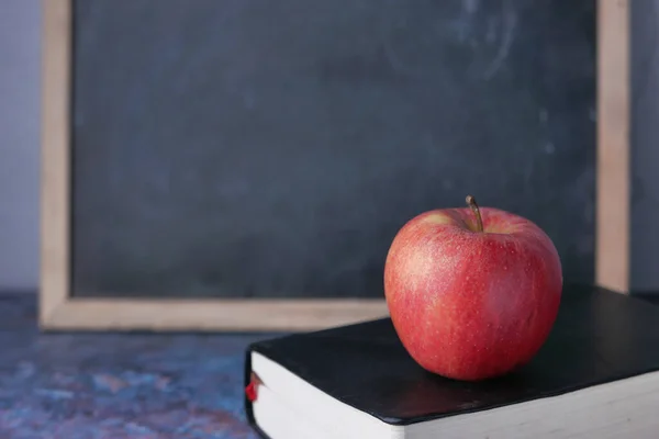 Apple on a book against black board, back to school Royalty Free Stock Photos