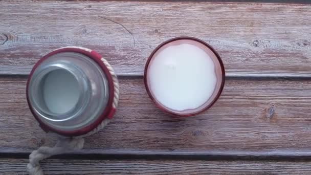 Πάνω όψη του γυαλιού του γάλακτος και μπουκάλι γάλα στο τραπέζι — Αρχείο Βίντεο