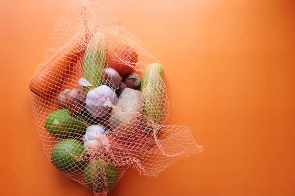 Close-up de legumes em um saco reutilizável em saco laranja — Fotografia de Stock