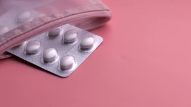 Beyaz hapların üst görünümü, pembe arka planda konteyner 