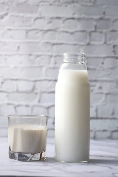 Lait frais dans un verre et bouteille sur la table — Photo