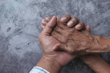 Young man holding hands with a senior lady.