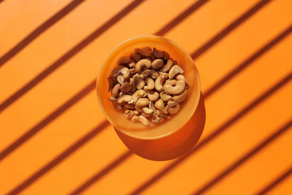 Vue du dessus de la noix de cajou dans un bol sur fond orange — Photo