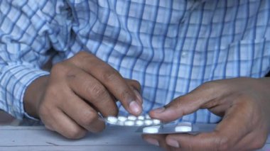 Close up of white pills on man hand, taking medicine concept 