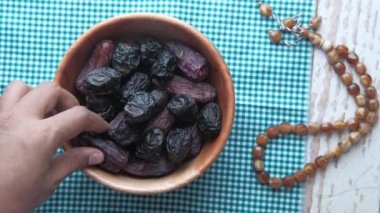 İnsan eli, kavalyeden hurma meyvesi alır. 