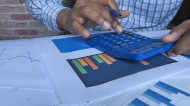 close up of person using calculator and analyzing charts 