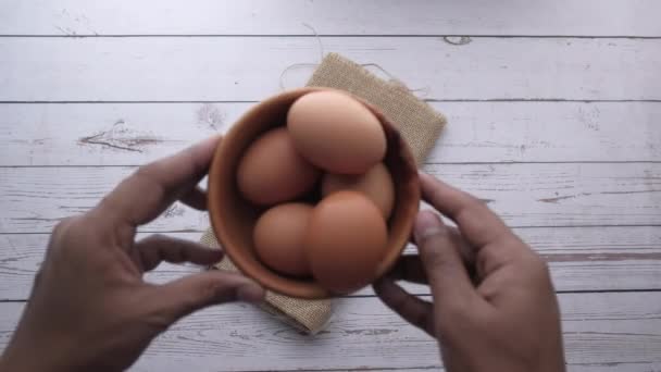 Bovenaanzicht van eieren in een kom op houten tafel — Stockvideo