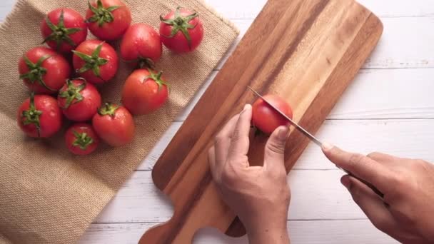 Vista superior del hombre corte a mano de tomate en la tabla de cortar — Vídeo de stock