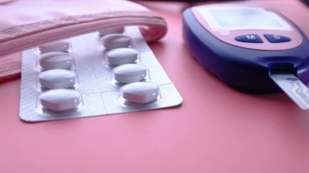 Glucosemeter, medicijn pillen en stethoscoop op roze achtergrond, — Stockvideo