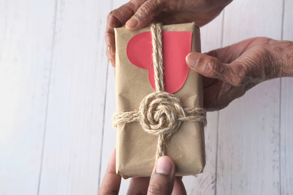 Senior woman giving gift box to young man — Stock Photo, Image