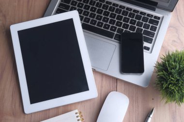 Dijital tabletin üst görünümü, dizüstü bilgisayar, akıllı telefon ve turuncu arkaplan üzerindeki not defteri 