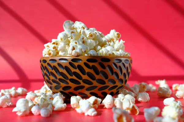 Popcorn in a wooden bowl in a red background — Stock fotografie