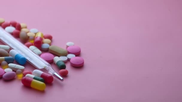 Close-up van pillen en thermometer op paarse achtergrond — Stockvideo