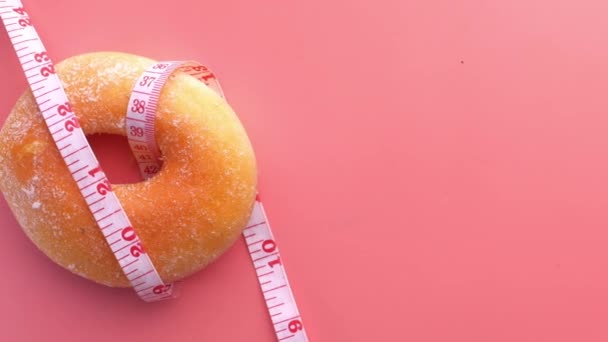 Замыкание измерительной ленты и пончиков на розовом фоне — стоковое видео