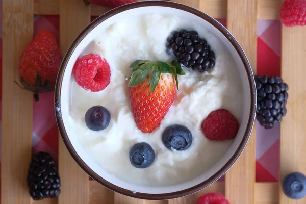 Bowl van bosbessen, aardbeien en yoghurt op houten tafel. — Stockfoto