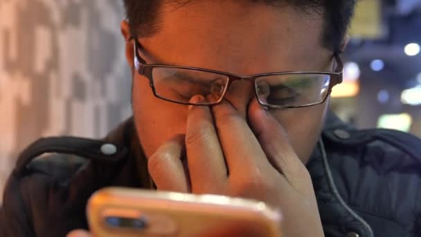 Young man suffering eye pain from using smart phone — Stock Video