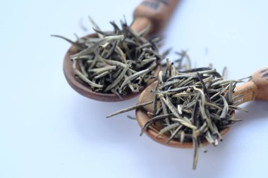 Ahşap zemin üzerinde kurumuş yeşil çay yaprağı ve toz yığını..