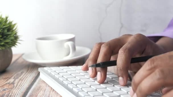 Primer plano de la mano del hombre escribiendo en el teclado en la mesa — Vídeos de Stock