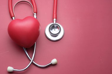 Pembe arka planda kalp şekli ve steteskop. 
