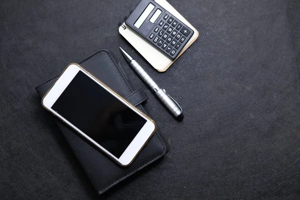 Top view of smart phone, notepad and calculator on black background — Stock Photo, Image
