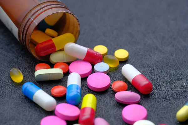 Primo piano di pillole colorate versando su uno sfondo rosso — Foto Stock
