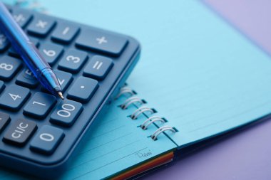 Mavi renkli kalem, hesap makinesi ve not defterini kapat