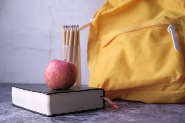 Яблуко на стопі книги зі шкільним мішком та телефоном — стокове фото