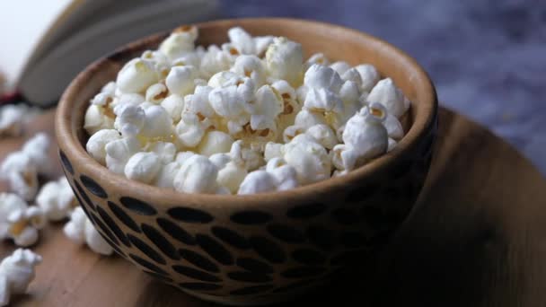 Popcorn in een kom en boek op tafel — Stockvideo