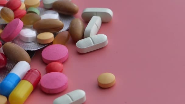 Крупным планом разноцветных таблеток, разливающихся на оранжевом фоне — стоковое видео