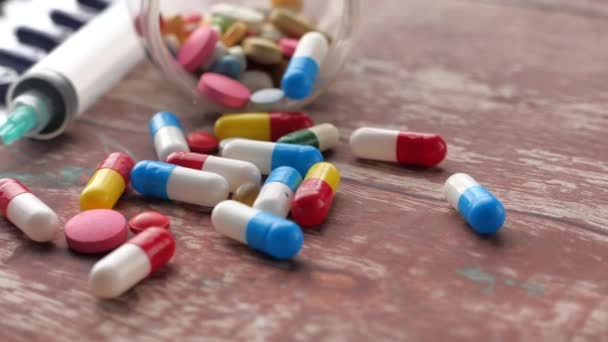 Close-up van kleurrijke pillen en spuit op houten achtergrond — Stockvideo