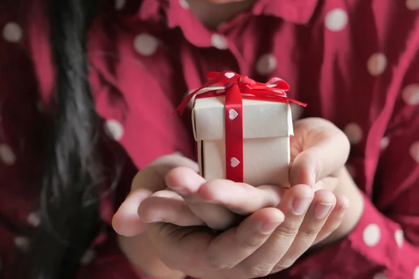 Valentines Day. Woman holding gift box with red bow over red background — Stock Photo, Image