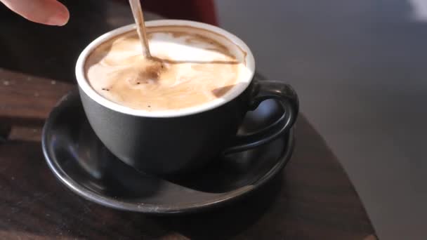 Young woman stirs cup of coffee with spoon. — Stock Video