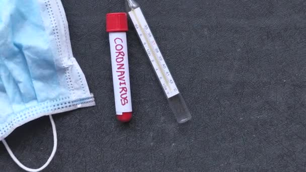 Close-up de máscara facial, tubo de teste de sangue e termômetro em fundo preto — Vídeo de Stock