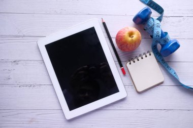 Beyaz arkaplanda dijital tablet ve halterin üst görünümü