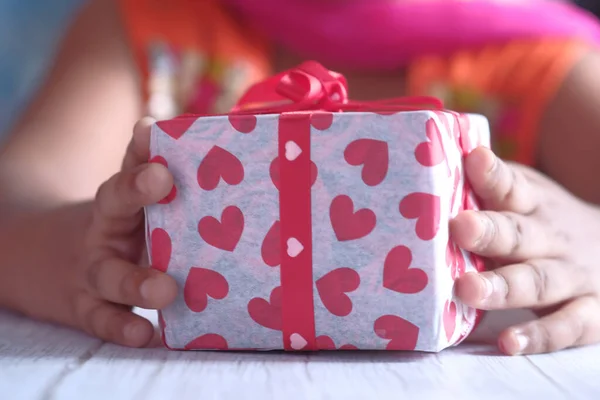 Niño niña mano celebración regalo en la mesa — Foto de Stock