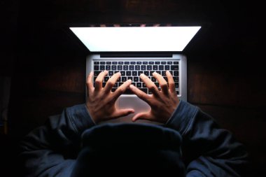 Kapüşonlu hacker geceleri laptoptan veri çalıyor. 