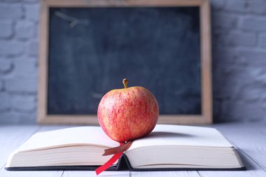 Masanın üzerinde açık bir kitap üzerinde elmayı kapat 