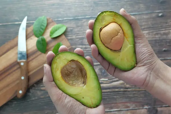 Hälften avokado frukt innehav för hand, frisk frukt. — Stockfoto