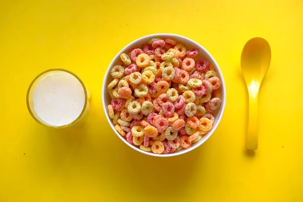 Colorful ring corn flakes in a bowl on yellow background — Stock Photo, Image