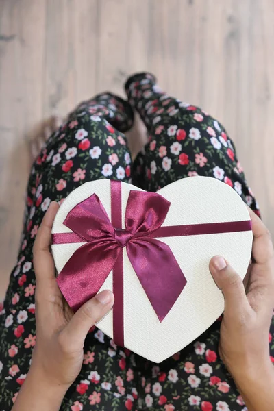 Las mujeres sostienen la mano regalo en forma de corazón y sobre en la mesa — Foto de Stock