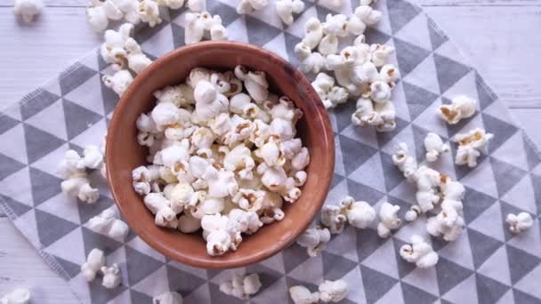 Palomitas de maíz en un tazón y derramamiento en la mesa — Vídeos de Stock