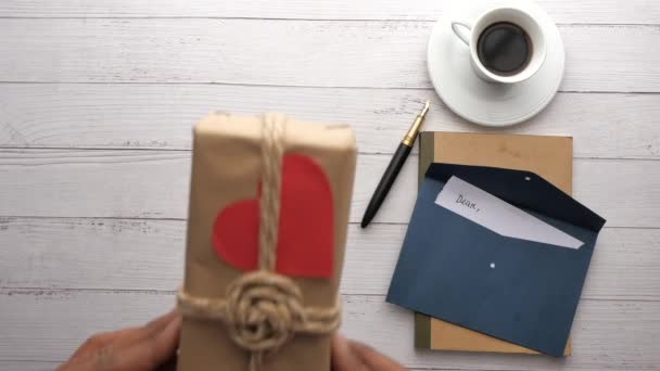 Mans mano mantenga la forma del corazón regalo y sobre en la mesa — Vídeo de stock