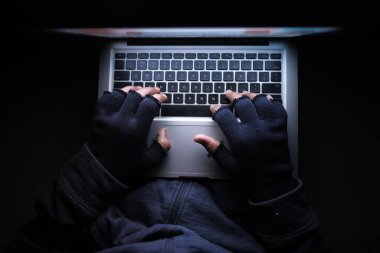 Kapüşonlu hacker geceleri laptoptan veri çalıyor. 