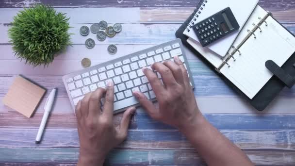 Primer plano de la mano del hombre escribiendo en el teclado en la mesa — Vídeos de Stock