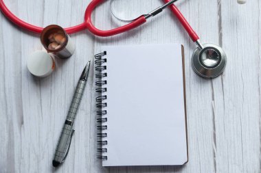 Steteskop, yapışkan notlar, not defteri ya da defter, tahta masadaki kalem.