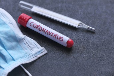 Yüz maskesi, kan testi tüpü ve renk arkaplanındaki termometreyi kapat 