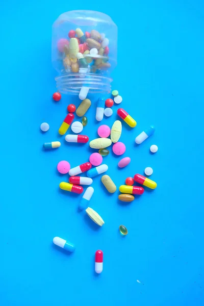 Pilules colorées se répandant sur fond bleu, vue de dessus — Photo