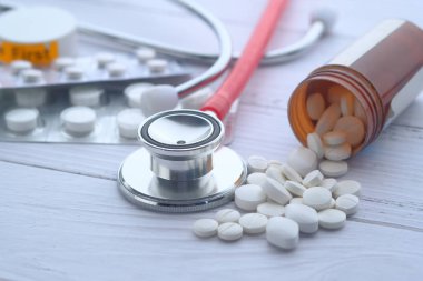 Beyaz arka planda haplar, ilaçlar ve steteskop, kapatın. 