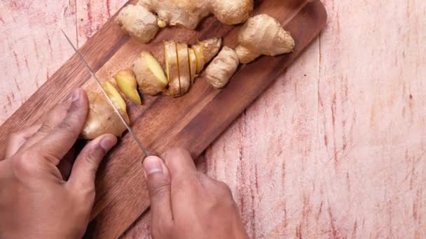 Top view of mans hand cutting ginger on chopping board — Stock Video