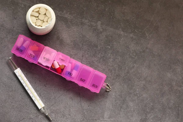 粉色背景的水泡包、温度计和药丸盒的顶部视图 — 图库照片